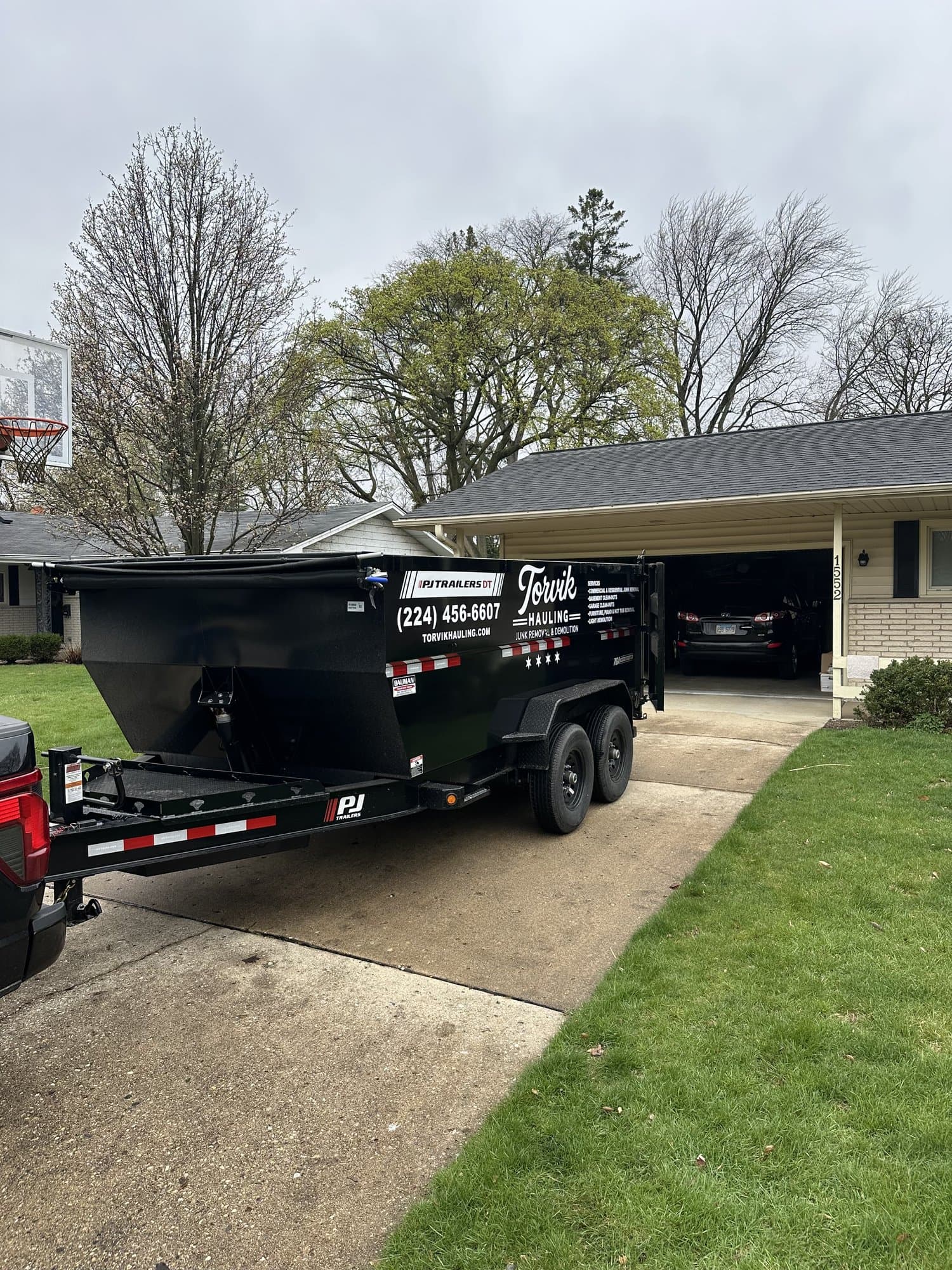 Front view of the Torvik Hauling dump trailer parked in a suburban driveway, ready for a load