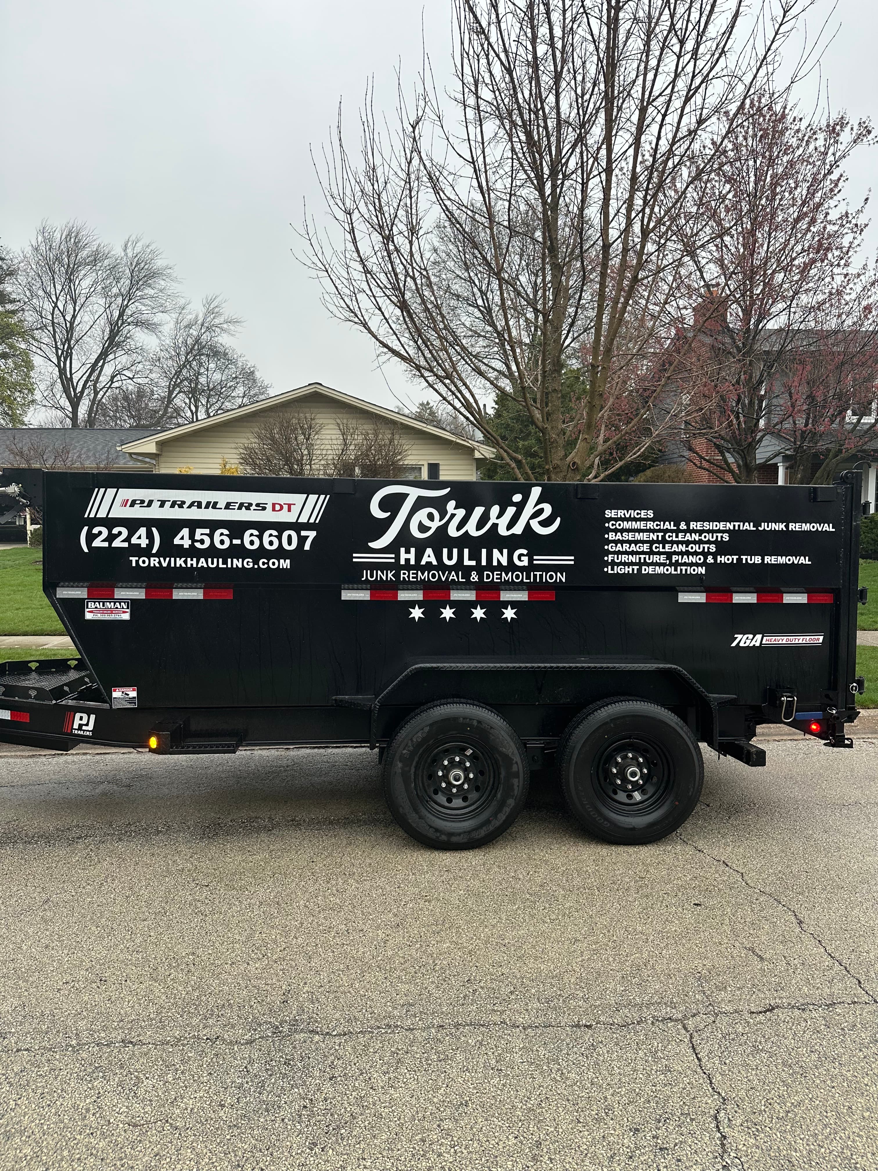 Side view of the Torvik Hauling dump trailer displaying the full services list and phone number (224) 456-6607